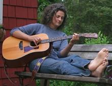 photo of Sara Thomsen sitting outside playing guitar