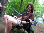 photo of Drew Grunseth sitting in a chair in a campsite in the woods